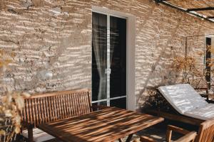 a wooden table and bench on a patio with a brick wall at Mà C'a - Casa Privata in Praiano