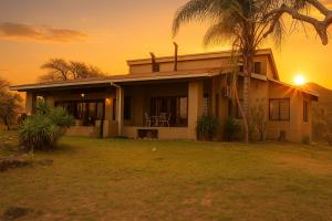 a house with a palm tree in front of a sunset at The Sanctuary- Self Catering Accommodation in Nelspruit