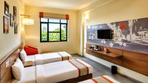 ein Hotelzimmer mit zwei Betten und einem Fernseher in der Unterkunft Max Hotels Jabalpur in Jabalpur