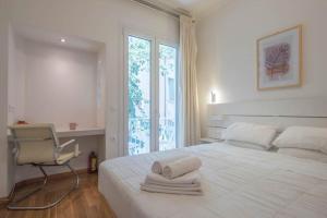 a white bedroom with a bed and a chair and a window at Syntagma Gem 1 in Athens