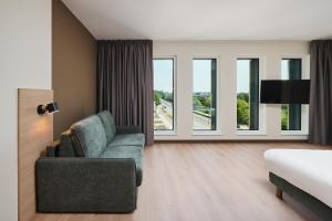 a hotel room with a couch and a bed and windows at Première Classe Warsaw Airport in Warsaw