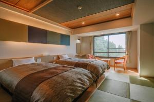 a bedroom with two beds and a table and a window at Kirishima Hotel in Kirishima +24 photos