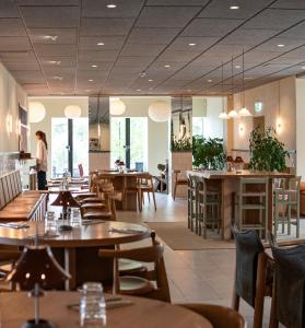 a restaurant with tables and chairs and a person in the background at Vår Gård Saltsjöbaden in Saltsjöbaden