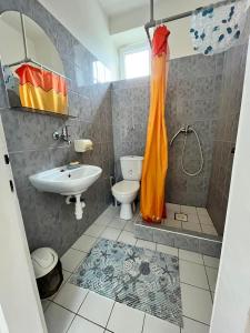 a bathroom with an orange shower curtain and a sink at Ubytovanie Klára in Veľký Meder