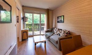 a living room with a couch in front of a window at Résidence Vacancéole Les Chalets d'Ax in Ax-les-Thermes