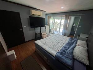 a bedroom with a bed and a flat screen tv at Baan Mo in Ban Kata