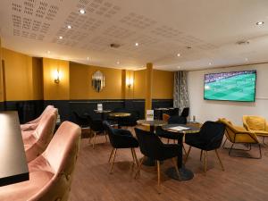 a waiting room with tables and chairs and a tv at Logis Hotel Center in Brest
