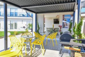 a patio with yellow chairs and a grill at Vila Manuela Techirghiol in Techirghiol