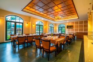 a dining room with tables and chairs and windows at HOTEL MARIAPARK KALLooRKKAD in Vāzhākulam