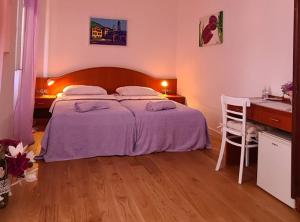 a bedroom with a large bed with a desk and a desk at Rooms Milena in Lopud