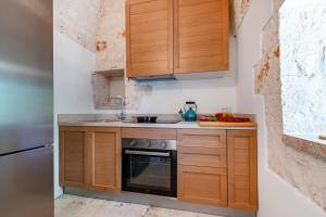 a kitchen with wooden cabinets and a sink and a stove at Lamia Terra 3BR, Terrace & BBQ - Happy Rentals in Castellana Grotte