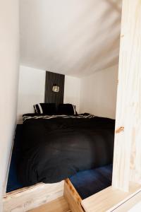 a bedroom with a black bed in a room at Le Nid Cozy - Appart avec Piscine, Terrain de Tenis et Balcon in Métabief +18 photos