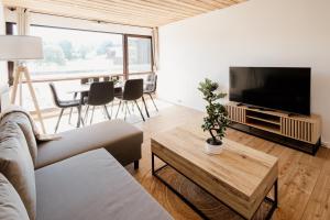 a living room with a couch and a tv and a table at Le Nid Cozy - Appart avec Piscine, Terrain de Tenis et Balcon in Métabief