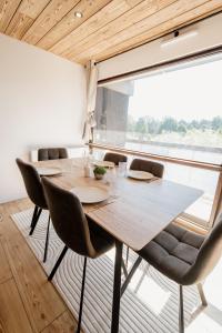 a wooden table and chairs in a room with a large window at Le Nid Cozy - Appart avec Piscine, Terrain de Tenis et Balcon in Métabief