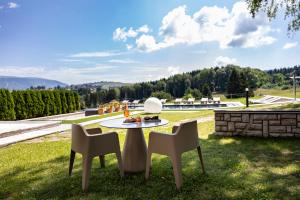 Ein Tisch und Stühle stehen auf einem Rasenfeld. in der Unterkunft Linta Hotel Wellness & Spa in Asiago