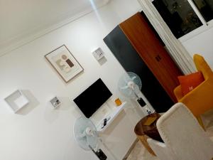 a white living room with a fan and a chair at Cosy Masta 1 in Pointe-Noire