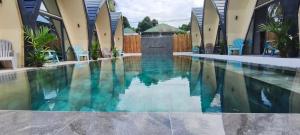 a swimming pool in the middle of a house with blue chairs at Lokal Hotels Dauin in Dauin