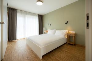 a bedroom with a white bed and a window at Résidence du Lys - Perrin Apartments in Luxembourg