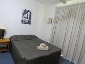 a bedroom with a bed with a towel on it at Emerald Gardens Motel & Apartments in Emerald