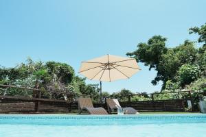 a pool with two chairs and an umbrella at REQUIES first bloom in Kawazu