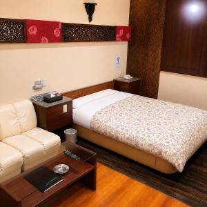 a bedroom with a bed and a couch and a table at 名古屋北区のホテルコアラ in Tsujichō