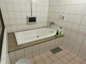 a bath tub in a tiled bathroom with a tv at 名古屋北区のホテルコアラ in Tsujichō