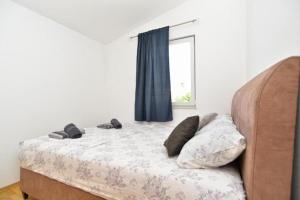 a bed with slippers on it in a room with a window at Apartman Mara in Pomer