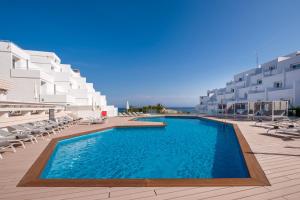 a swimming pool on a resort with chairs and buildings at Barceló Portinatx - Adults Only in Portinatx