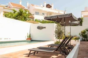 a group of chairs and an umbrella next to a swimming pool at Vida na Vila in Vila Nova de Milfontes