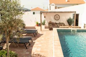 a backyard with a swimming pool and benches next to a house at Vida na Vila in Vila Nova de Milfontes