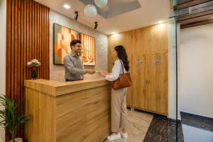 a man and a woman shaking hands at a counter at Perfectstayz AIIMS near Aiims Hospital in Rishīkesh +57 photos