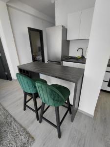 a kitchen with a table and two green chairs at B&L Apartmani in Sutomore