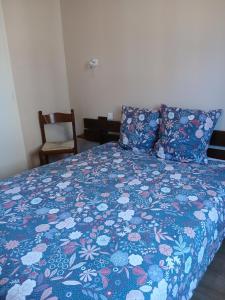 a bedroom with a bed with a blue comforter and a chair at Hôtel de Cenves in Cenves
