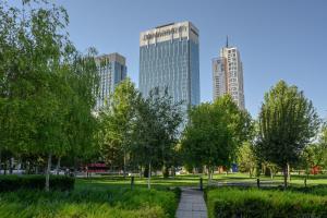 a park with trees and buildings in the background at JW Marriott Hotel Tashkent in Tashkent