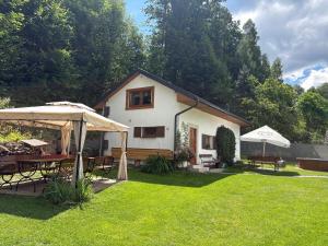 a house with a yard with tables and umbrellas at Penzion U Rodinky in Bělá pod Pradědem