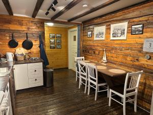 a kitchen with a wooden wall with a table and chairs at Astra Whale - Waterfront Boutique Hostel in Lofoten in Kabelvåg