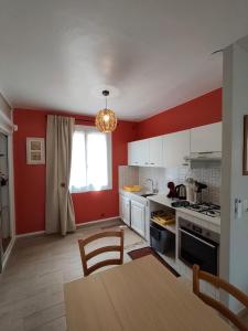a kitchen with red walls and a table and a dining room at le maquis in Sisco