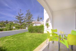 a patio with green chairs and a table and grass at Torrenueva Park Apartments in La Cala de Mijas