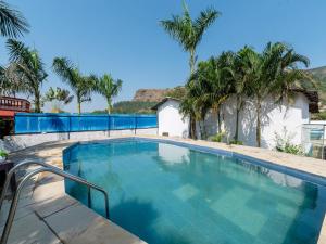 ein großer Swimmingpool mit Palmen im Hintergrund in der Unterkunft Palette Mountain Mist Villa | 2BHK | Jacuzzi | Pool | Lonavala in Lonavla