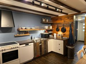 a kitchen with white appliances and wooden walls at Astra Whale - Waterfront Boutique Hostel in Lofoten in Kabelvåg