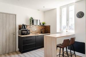 a kitchen with black cabinets and a counter with a microwave at L'Eden Spa - Jacuzzi - Saint-Etienne in Saint-Étienne +28 photos
