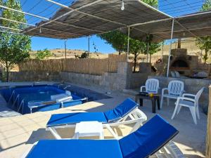 a patio with a swimming pool with chairs and a table at Beit El Jabal in Al Mudayrij