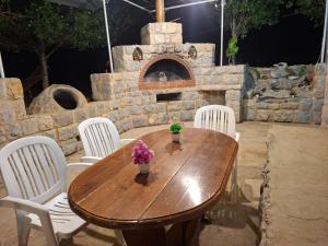 a wooden table with white chairs and a stone oven at Beit El Jabal in Al Mudayrij