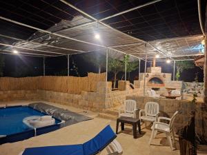 a patio with a swimming pool with chairs and a table at Beit El Jabal in Al Mudayrij +6 photos