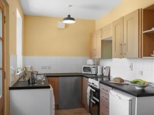 a kitchen with white appliances and wooden cabinets at Rose Cottage - Uk52178 in Leven