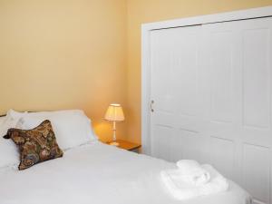 a bedroom with a white bed with a pillow and a lamp at Rose Cottage - Uk52178 in Leven +11 photos