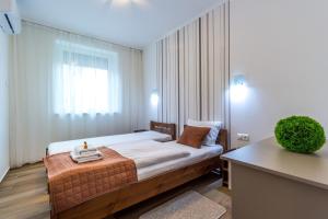 sypialnia z łóżkiem w pokoju z oknem w obiekcie Aqualiget-Apartmanház w Segedynie