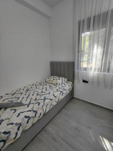 a white bedroom with a bed and a window at B&L Apartmani in Sutomore