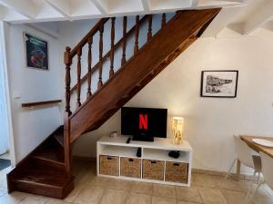 a living room with a staircase with a tv on a cabinet at Samour House - Centre ville in Saint-Vaast-la-Hougue