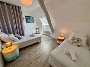 a bedroom with two beds and a table and a window at Samour House - Centre ville in Saint-Vaast-la-Hougue